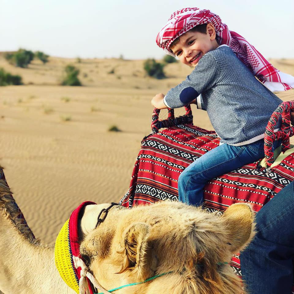 Kiki Conomos' son riding a camel in Dubai