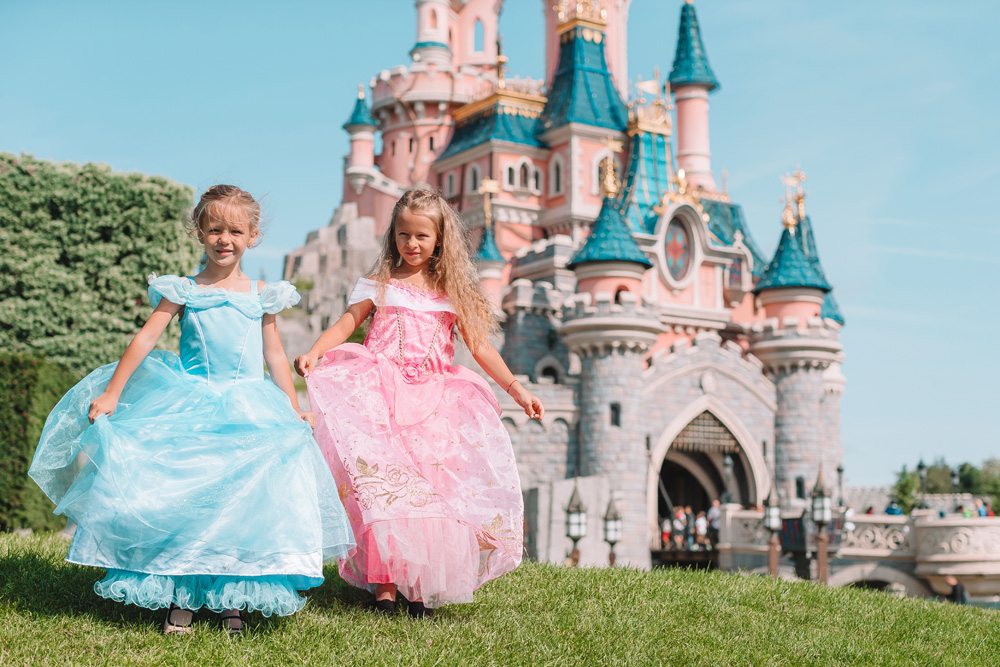 Little cute happy girls in beautiful princess at fairy-tale park